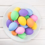 Colorful pastel easter eggs on white wooden background